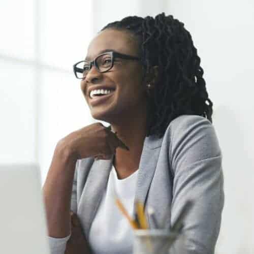 african american businesswoman laughing sitting against window in office e1631573683612 Buro